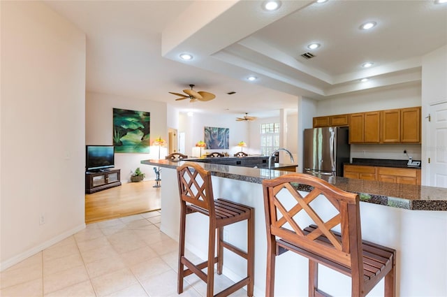 9908 Alafia River Ln, Gibsonton, FL 33534 - kitchen with freestanding refrigerator, a kitchen bar, brown cabinetry, recessed lighting, and tile counters