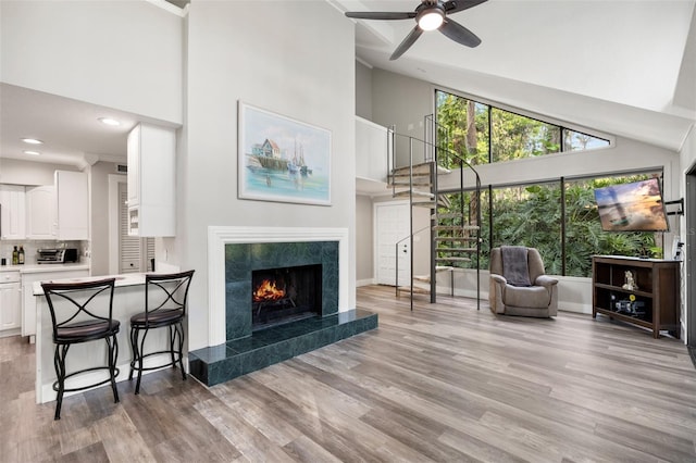 22004 Dupree Dr, Land O Lakes, FL 34639 - living room with high vaulted ceiling, light wood finished floors, baseboards, ceiling fan, and a tile fireplace