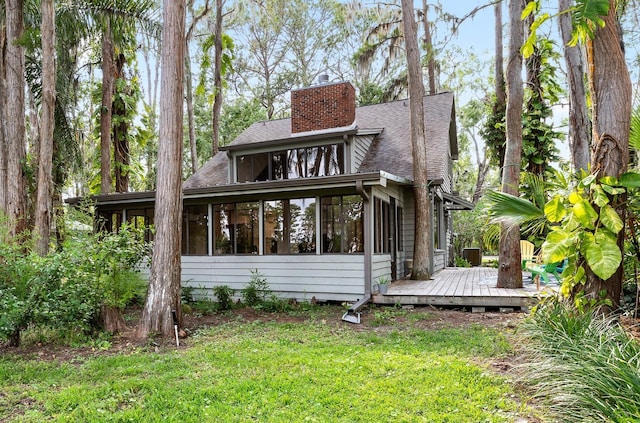 22004 Dupree Dr, Land O Lakes, FL 34639 - rear view of house with a sunroom, a wooden deck, a chimney, a shingled roof, and a yard