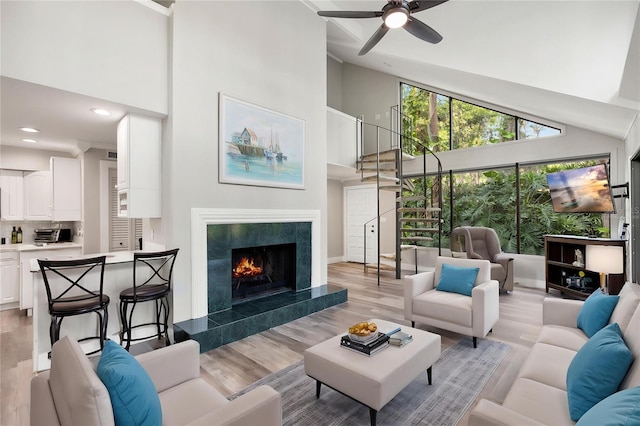 22004 Dupree Dr, Land O Lakes, FL 34639 - living area featuring a towering ceiling, light wood finished floors, ceiling fan, a tile fireplace, and baseboards