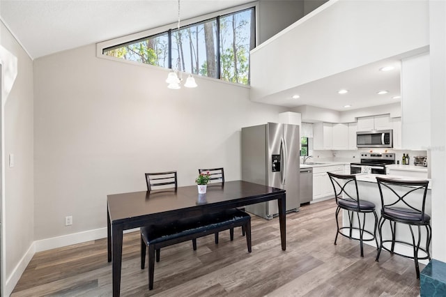 22004 Dupree Dr, Land O Lakes, FL 34639 - dining space featuring a chandelier, light wood-type flooring, baseboards, a towering ceiling, and recessed lighting