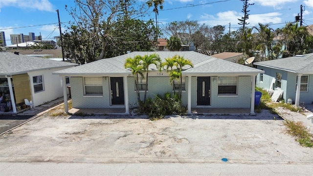 154 147th Ave E, Madeira Beach, FL 33708 - view of front facade with brick siding, roof with shingles, and a porch