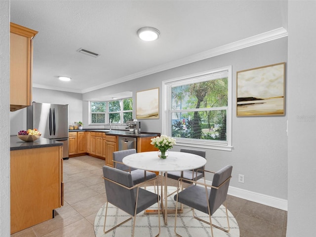 1701 38th St N, Saint Petersburg, FL 33713 - kitchen featuring ornamental molding, dark countertops, stainless steel appliances, baseboards, and light tile patterned flooring