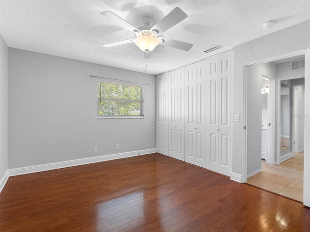 1701 38th St N, Saint Petersburg, FL 33713 - unfurnished bedroom with wood-type flooring, baseboards, a textured ceiling, a ceiling fan, and a closet