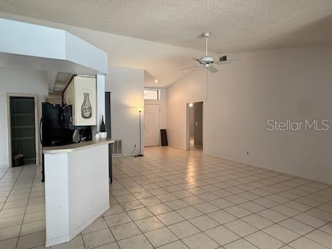 10811 Candlin Ct, Riverview, FL 33578 - kitchen featuring ceiling fan, open floor plan, light tile patterned floors, a textured ceiling, and freestanding refrigerator