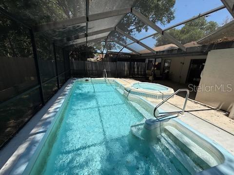 10811 Candlin Ct, Riverview, FL 33578 - view of pool featuring glass enclosure, a pool with connected hot tub, and a patio area