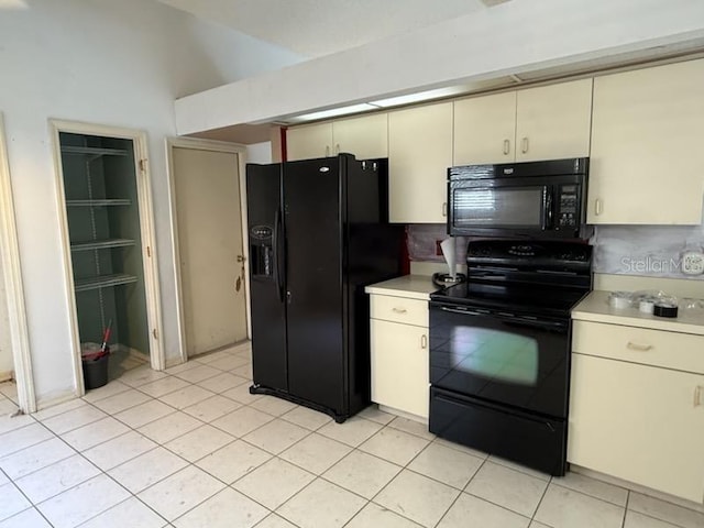 10811 Candlin Ct, Riverview, FL 33578 - kitchen featuring black appliances, cream cabinetry, light countertops, light tile patterned flooring, and lofted ceiling