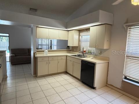 10811 Candlin Ct, Riverview, FL 33578 - kitchen with dishwasher, light countertops, a sink, vaulted ceiling, and light tile patterned floors