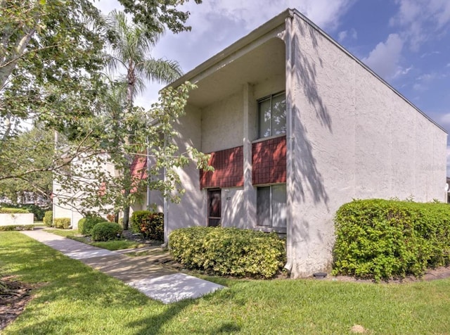 1877 Pine Cone Cir, Clearwater, FL 33760 - view of side of home with stucco siding and a yard