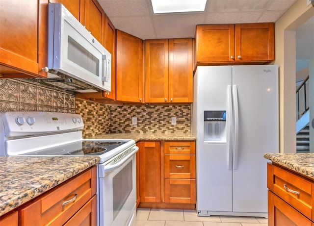 1877 Pine Cone Cir, Clearwater, FL 33760 - kitchen featuring white appliances, tasteful backsplash, light stone countertops, brown cabinets, and light tile patterned floors