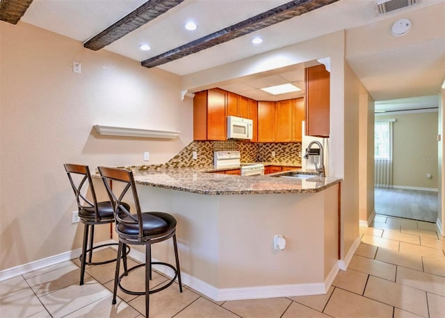 1877 Pine Cone Cir, Clearwater, FL 33760 - kitchen with white appliances, light stone countertops, a sink, decorative backsplash, and a peninsula