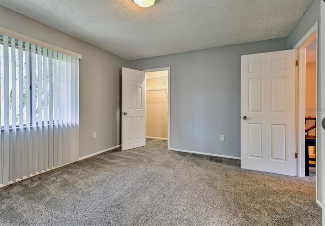 1877 Pine Cone Cir, Clearwater, FL 33760 - unfurnished bedroom with carpet flooring, a textured ceiling, a walk in closet, baseboards, and a closet