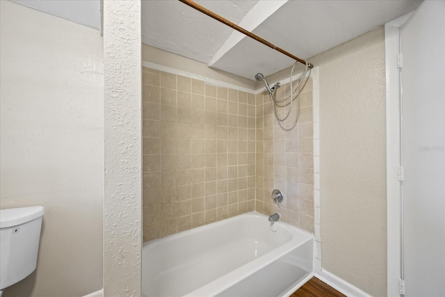 4804 N 18th St, Tampa, FL 33610 - bathroom with washtub / shower combination, toilet, a textured wall, and baseboards
