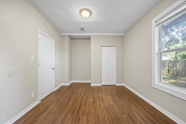 4804 N 18th St, Tampa, FL 33610 - empty room featuring dark wood-style flooring, healthy amount of natural light, a textured ceiling, and baseboards