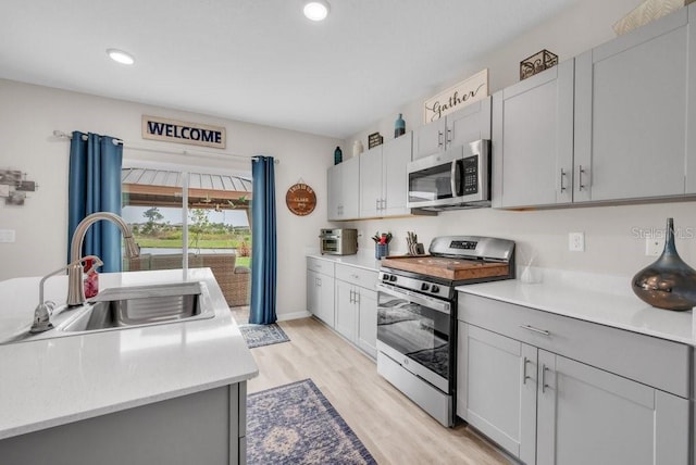 14643 Brumby Ridge Ave, Lithia, FL 33547 - kitchen with stainless steel appliances, a sink, light countertops, light wood finished floors, and recessed lighting