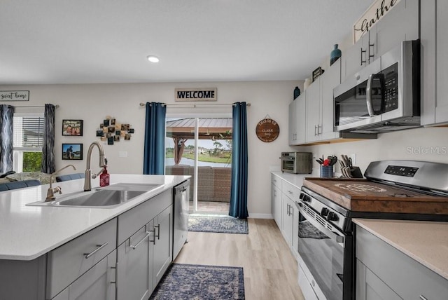 14643 Brumby Ridge Ave, Lithia, FL 33547 - kitchen with appliances with stainless steel finishes, a sink, gray cabinets, light wood-type flooring, and recessed lighting