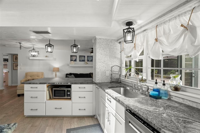 60 Lakeview Ct, Palm Harbor, FL 34683 - kitchen featuring stainless steel microwave, a sink, a peninsula, light wood-style floors, and dark stone countertops