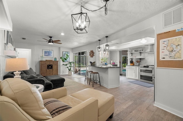 60 Lakeview Ct, Palm Harbor, FL 34683 - living area featuring light wood finished floors, baseboards, a ceiling fan, a chandelier, and a textured ceiling