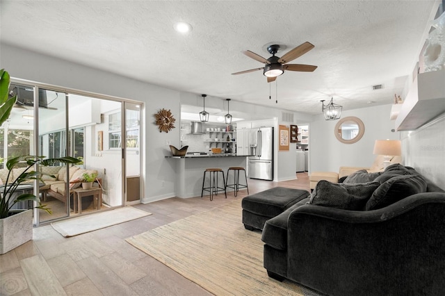 60 Lakeview Ct, Palm Harbor, FL 34683 - living room with ceiling fan, light wood finished floors, a textured ceiling, and a chandelier