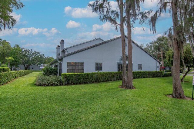 4234 Brentwood Park Cir, Tampa, FL 33624 - view of side of property featuring a yard, a chimney, and stucco siding