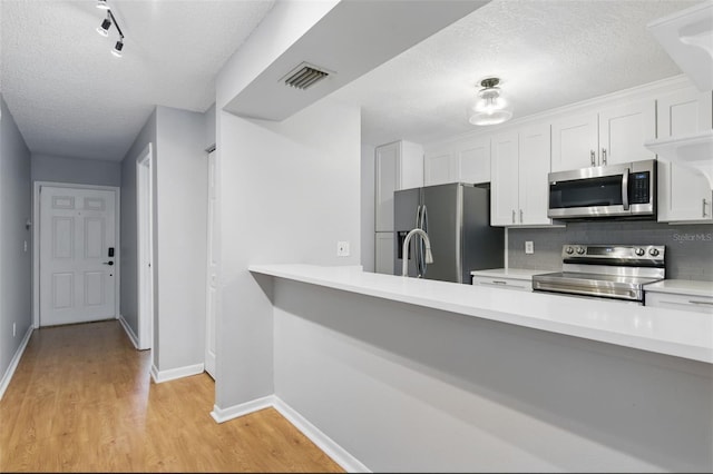 16109 Rambling Vine Dr E, Tampa, FL 33624 - kitchen with appliances with stainless steel finishes, a textured ceiling, light countertops, backsplash, and baseboards