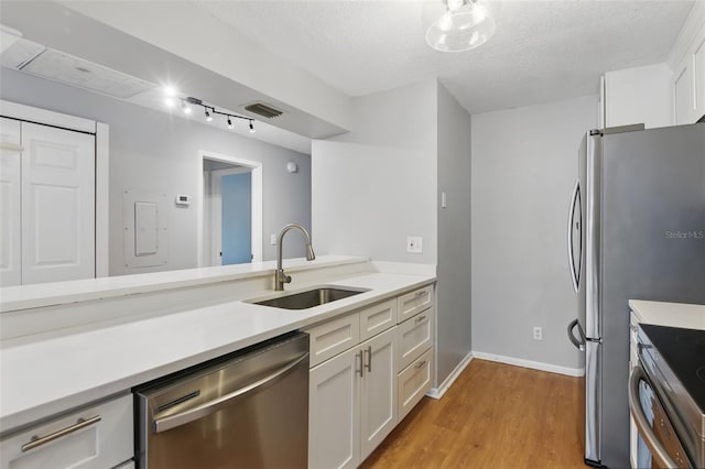 16109 Rambling Vine Dr E, Tampa, FL 33624 - kitchen with stainless steel appliances, a sink, white cabinetry, light wood-style floors, and light countertops