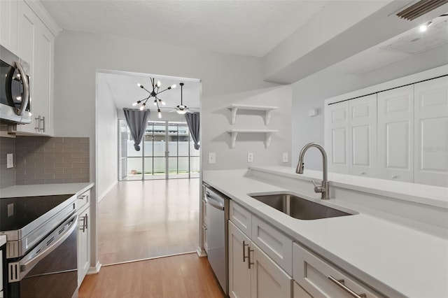 16109 Rambling Vine Dr E, Tampa, FL 33624 - kitchen with a sink, appliances with stainless steel finishes, light wood-style floors, open shelves, and light countertops