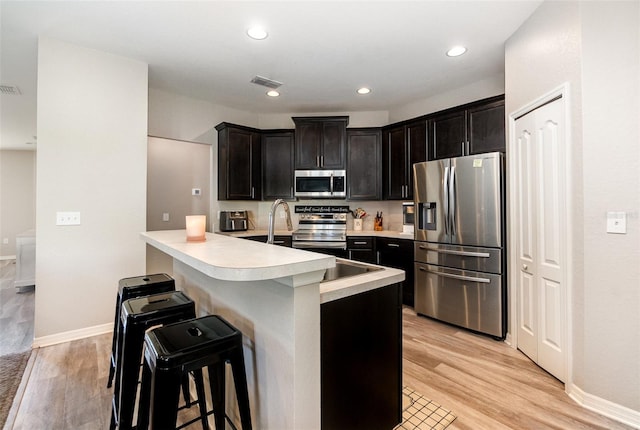 6050 Eagle Pointe Dr, Lakeland, FL 33812 - kitchen with appliances with stainless steel finishes, light countertops, a breakfast bar area, light wood finished floors, and recessed lighting