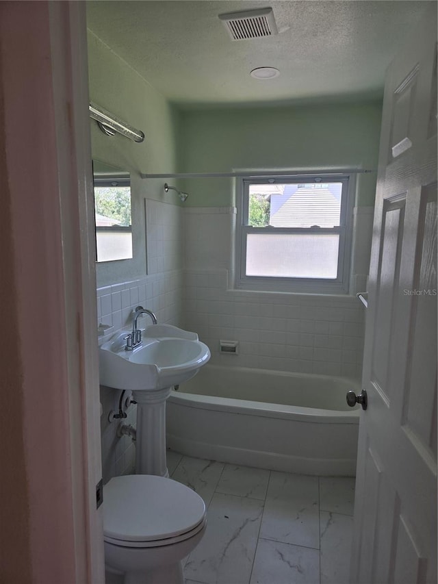 4611 17th Ave N, Saint Petersburg, FL 33713 - full bathroom with healthy amount of natural light,  shower combination, marble look tile flooring, toilet, and a textured ceiling