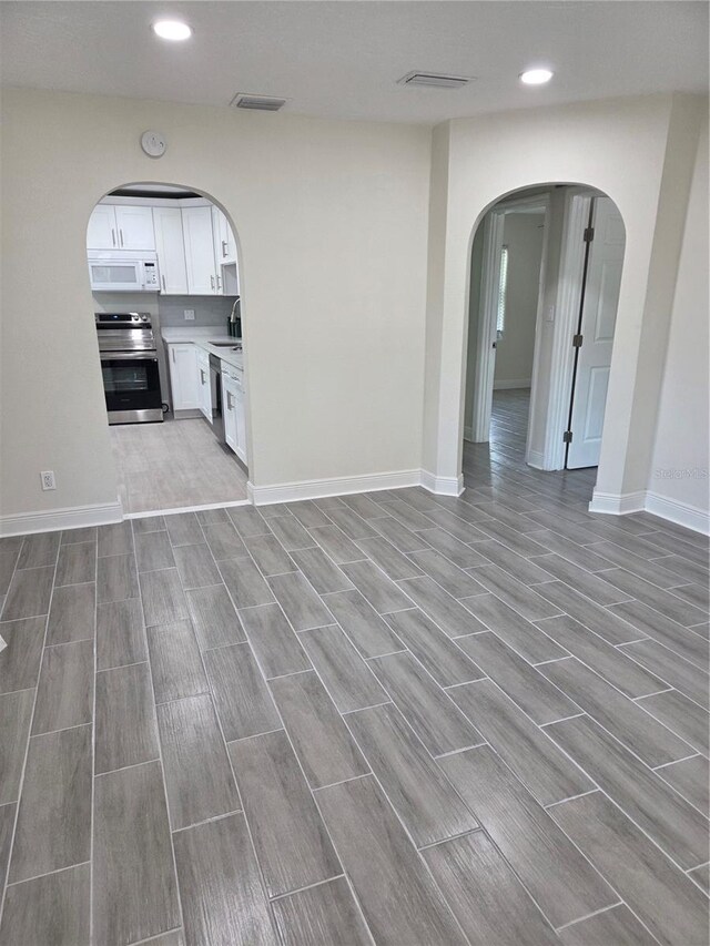 4611 17th Ave N, Saint Petersburg, FL 33713 - unfurnished living room featuring arched walkways, wood finish floors, recessed lighting, baseboards, and a sink