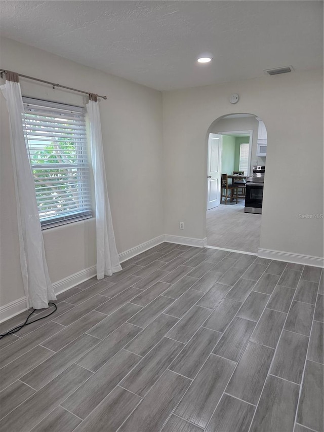 4611 17th Ave N, Saint Petersburg, FL 33713 - unfurnished room featuring arched walkways, wood tiled floors, baseboards, recessed lighting, and a textured ceiling