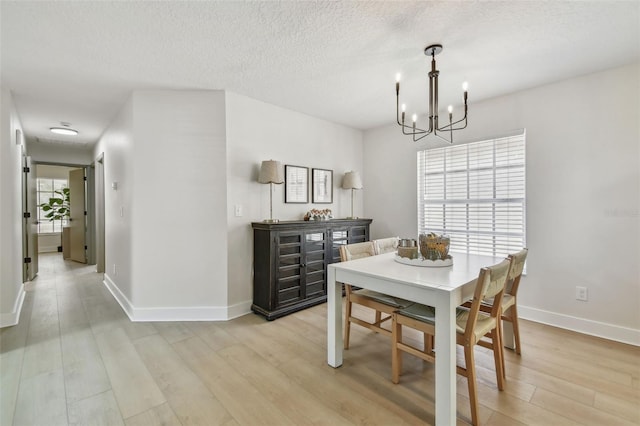 2742 Wilson Ct, Palm Harbor, FL 34684 - dining area featuring a chandelier, light wood-style floors, baseboards, and a textured ceiling