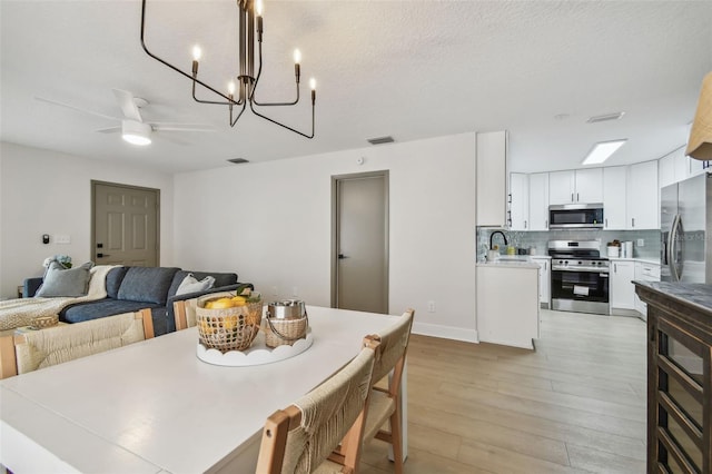 2742 Wilson Ct, Palm Harbor, FL 34684 - dining area featuring a ceiling fan, light wood-type flooring, a chandelier, and baseboards