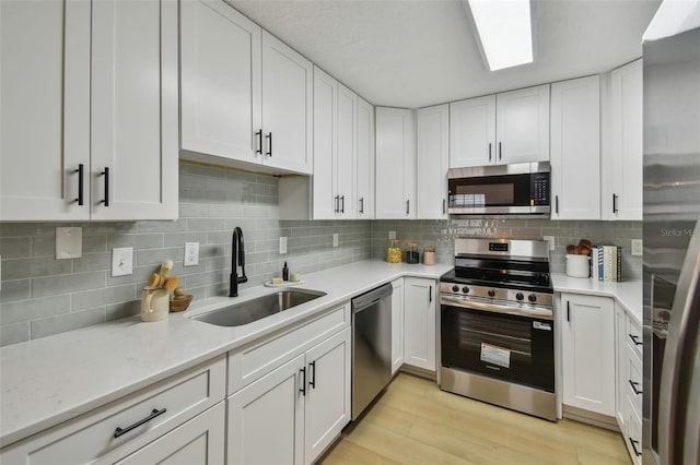 2742 Wilson Ct, Palm Harbor, FL 34684 - kitchen with appliances with stainless steel finishes, a sink, light countertops, and white cabinetry