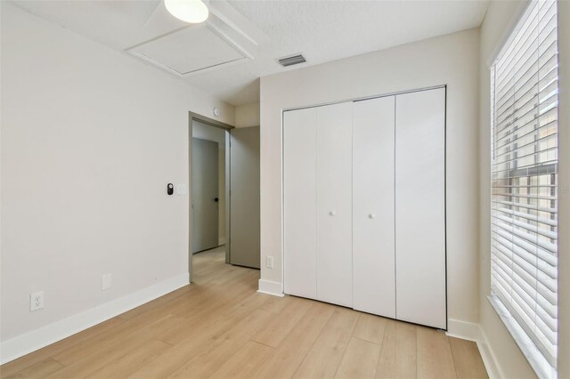 2742 Wilson Ct, Palm Harbor, FL 34684 - unfurnished bedroom featuring light wood-type flooring, a closet, baseboards, and attic access