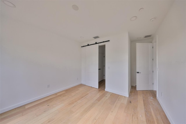 1801 N Morgan St Unit 5, Tampa, FL 33602 - unfurnished bedroom featuring a barn door, light wood-style floors, baseboards, and a walk in closet