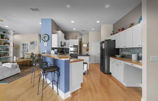 8701 Lake Calm Ln, Odessa, FL 33556 - kitchen featuring appliances with stainless steel finishes, a peninsula, tasteful backsplash, light wood-type flooring, and recessed lighting