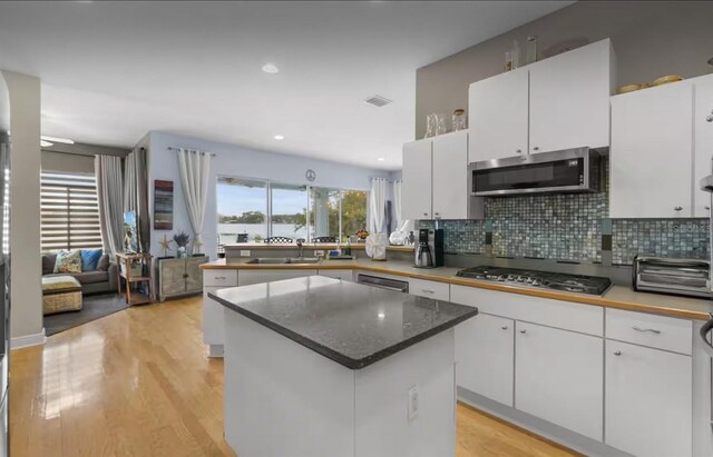 8701 Lake Calm Ln, Odessa, FL 33556 - kitchen featuring appliances with stainless steel finishes, white cabinetry, a sink, light wood-type flooring, and tasteful backsplash