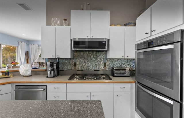 8701 Lake Calm Ln, Odessa, FL 33556 - kitchen featuring appliances with stainless steel finishes, white cabinetry, and decorative backsplash