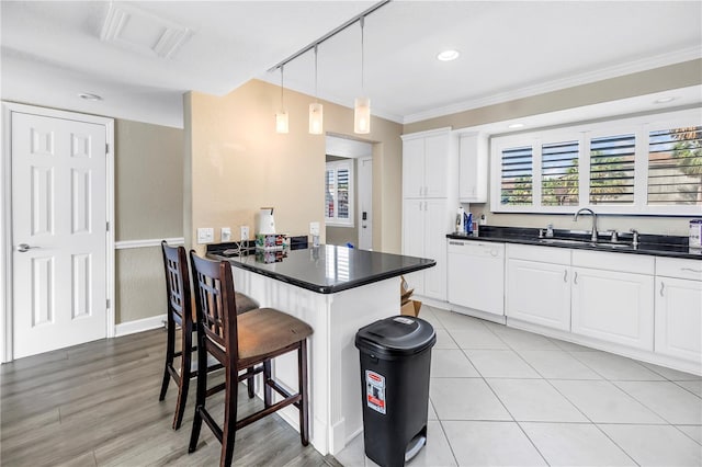 6309 Newtown Cir Unit 9B2, Tampa, FL 33615 - kitchen with white dishwasher, a sink, a kitchen breakfast bar, dark countertops, and crown molding