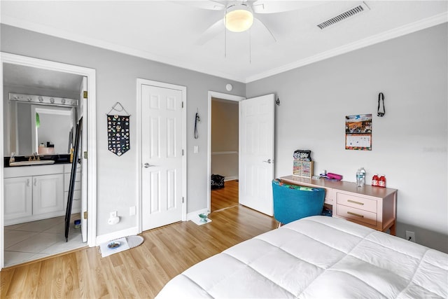 6309 Newtown Cir Unit 9B2, Tampa, FL 33615 - bedroom featuring a sink, light wood-type flooring, ornamental molding, ensuite bath, and a ceiling fan