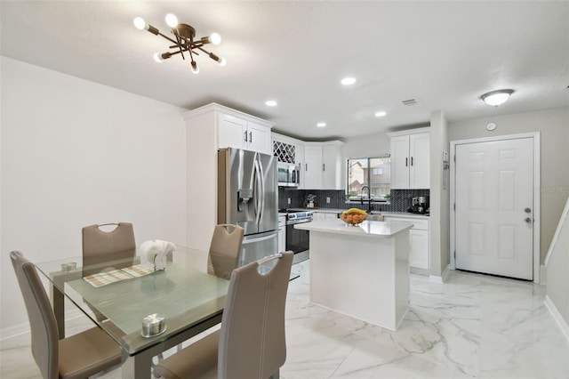 4017 Cedar Limb Ct, Tampa, FL 33614 - kitchen featuring stainless steel appliances, light marble finish flooring, tasteful backsplash, white cabinetry, and light countertops