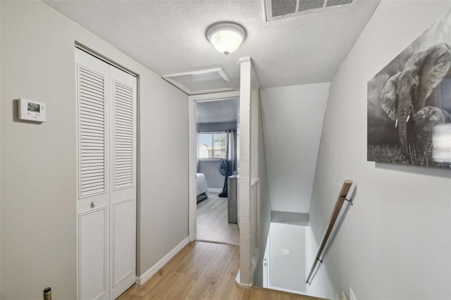 4017 Cedar Limb Ct, Tampa, FL 33614 - hallway with an upstairs landing, light wood-style floors, a textured ceiling, attic access, and baseboards