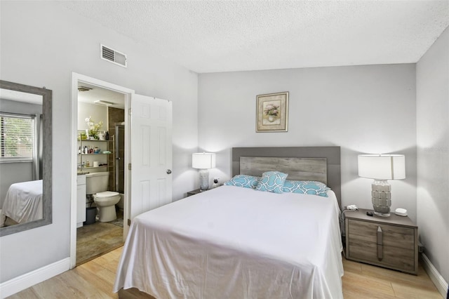 4017 Cedar Limb Ct, Tampa, FL 33614 - bedroom featuring light wood-style floors, a textured ceiling, baseboards, and connected bathroom