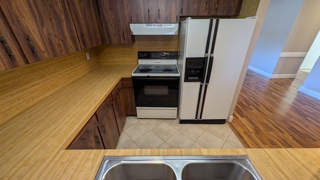 4021 19th St N, Saint Petersburg, FL 33714 - kitchen with white refrigerator with ice dispenser, electric stove, extractor fan, light tile patterned floors, and dark brown cabinetry