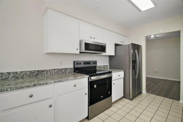 9755 SE 176th St, Summerfield, FL 34491 - kitchen featuring stainless steel appliances, white cabinetry, light tile patterned floors, baseboards, and light stone countertops