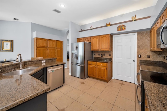 1516 E Lake Woodlands Pkwy, Oldsmar, FL 34677 - kitchen with appliances with stainless steel finishes, a sink, backsplash, light tile patterned floors, and dark stone countertops
