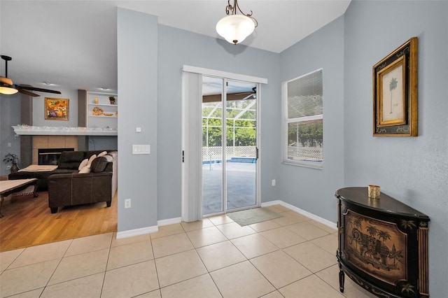 1516 E Lake Woodlands Pkwy, Oldsmar, FL 34677 - doorway to outside with a ceiling fan, light tile patterned floors, baseboards, and a tiled fireplace