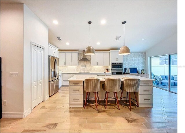 12010 Jackson Landing Pl, Tampa, FL 33624 - kitchen with appliances with stainless steel finishes, wall chimney range hood, decorative backsplash, light countertops, and white cabinets