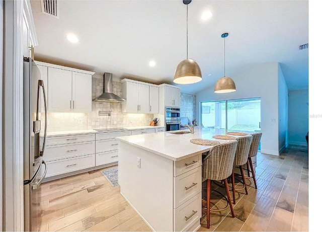 12010 Jackson Landing Pl, Tampa, FL 33624 - kitchen with wall chimney exhaust hood, appliances with stainless steel finishes, a breakfast bar, tasteful backsplash, and white cabinetry